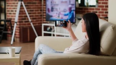Employee doing remote work while in digital videoconference meeting on smartphone. Young adult person working from home while discussing with colleagues on virtual video call conference.
