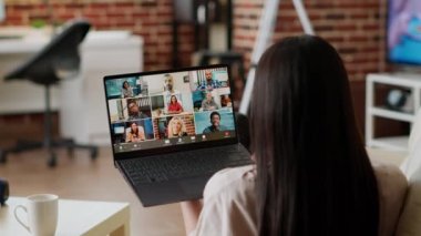 Woman working from home while discussing with manager on digital video call conference. Young adult person with portable computer working remotely while having online virtual teleconference.