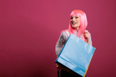 Shopaholic woman smiling after buying clothes in colorful shopping bags, using money to purchase things at retail store on sale discount. Carrying bags package, feeling trendy and happy.