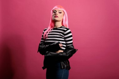 Portrait of attractive cute person wearing sexy leather jacket to advertise rocker fashion style with punk hairstyle. Carefree model feeling stylish and confident with elegant clothes in studio.