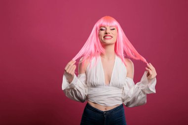 Portrait of caucasian woman smiling in front of camera, wearing pink hair wig and elegant trendy clothes. Stylish fashion item to feel confident and attractive, candid smile over background.