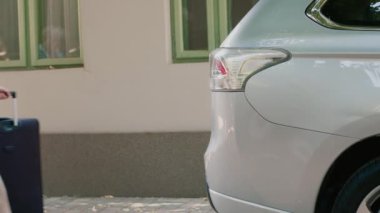 Elder people loading vehicle with baggage and trolleys while going on marriage anniversary citybreak. Senior couple going on retirement holiday vacation while putting voyage luggage inside car trunk