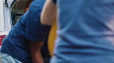 Multicultural people putting luggage in vehicle trunk while getting ready for summer citybreak. Mother, daughter and family friends going on field trip while loading car with baggage and trolleys.