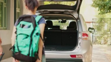 Casual couple putting voyage baggage inside vehicle trunk while getting ready for summer holiday citybreak. Married people loading baggage and trolleys inside car while going on field trip vacation.