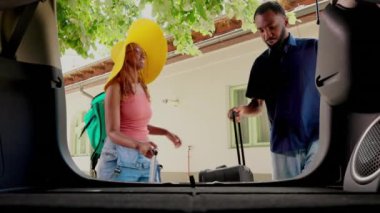 Boyfriend and girlfriend going on field trip while putting baggage inside vehicle. Happy couple loading luggage inside car trunk while going on marriage anniversary summer holiday citybreak