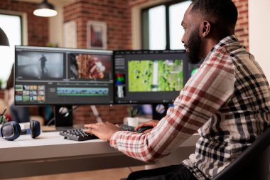 African american filmmaker creating video footage using editing sofware to make post production content. Using color grading and visual or audio effects to edit film montage project at home.