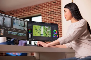 Asian videographer working on editing video and audio footage with professional software to create film content for post production. Using movie montage to edit multimedia movie.