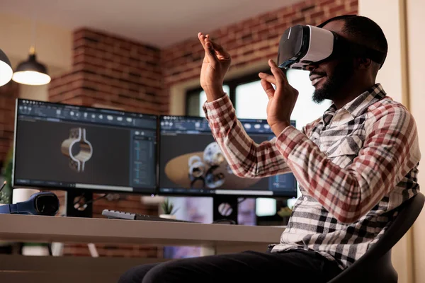 African american developer manufacturing engine gears using vr glasses with 3d simulation and cad software on computer. Techinican developing industrial machinery product with interactive goggles.