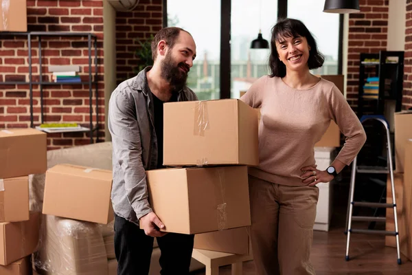Portrait of caucasian couple carrying boxes to move in apartment property, using furniture storage to decorate family home. Enjoying household relocation to start new beginnings.