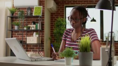 Business student taking notes at online webinar class on laptop, doing remote work and distant education lesson. Working remotely on startup and learning modern freelance job at home.