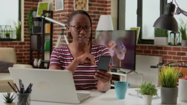 Freelancer using teleconference call to talk to colleagues, working remotely and attending videocall conference meeting on mobile phone. Chatting on videoconference with webcam from home.