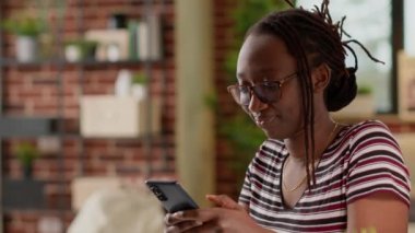 Afrika kökenli Amerikalı bir kadın sosyal medya ağında mesajlaşmak için akıllı telefon kullanıyor. Evde bilgisayarla çalıştıktan sonra ara verip cep telefonuyla sohbet etmek, serbest çalışmak..