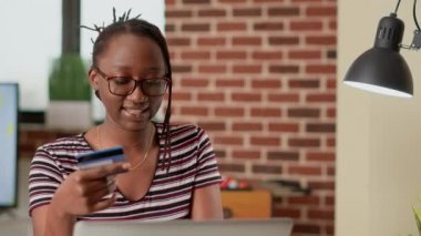 Young adult using credit card to do online shopping on laptop, buying clothes on online retail store website. Making electronic transaction and internet payment to buy on discount.