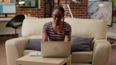 Young woman using credit card to shop online on website, buying clothes from retail store. Shopaholic adult making money payment and electronic transaction, doing purchase on sale.
