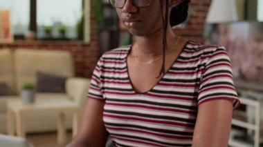 Female freelancer working remotely on laptop from home, using computer and notebook to attend online webinar at do remote work. Browsing internet network to do freelance job at desk.