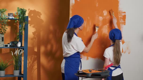 Small Family Renovating House Walls Orange Paint Color Using Paintbrush — Vídeo de Stock