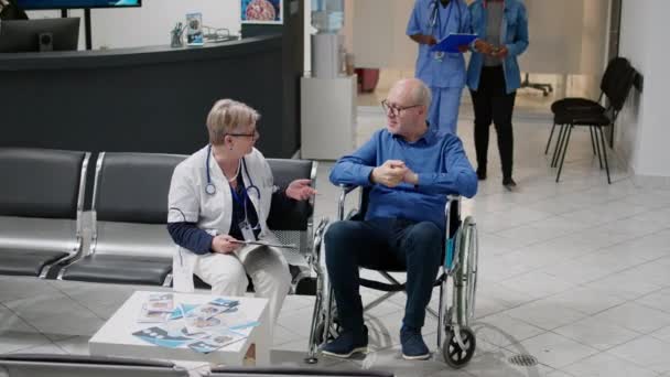 Caretaker Helping Senior Man Disability Checkup Visit Hospital Reception Woman — Vídeos de Stock