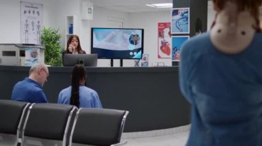 Woman in pain wearing cervical neck collar at hospital reception, waiting to attend medical checkup visit with specialist and treat accident injury. Patient in waiting room area at clinic.