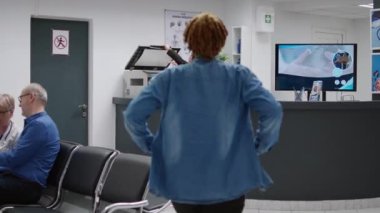 Asian receptionist working with medical reports at reception counter desk in hospital lobby waiting room. Employee helping with healthcare appointments and consultations, clinical center.
