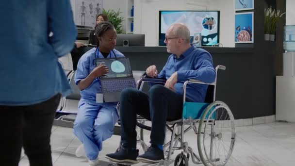 Νοσοκόμα Που Δείχνει Ανθρώπινο Νευρικό Σύστημα Στον Χρήστη Αναπηρικού Αμαξιδίου — Αρχείο Βίντεο