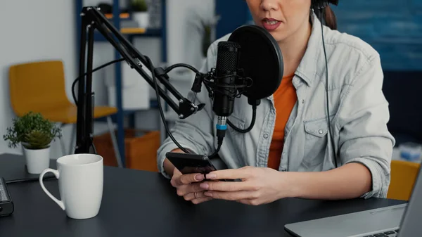 Famous online live radio talk show using smartphone to answer audience messages. Popular social media influencer talking with public on live chat on mobile cell phone. Studio shoot