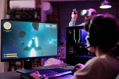 Woman playing shooter video games championship on pc, in living room with neon lights. Female gamer enjoying action gameplay competition to do live stream online, having fun on internet.