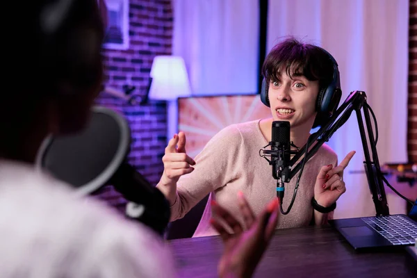 Female presenter interviewing young woman with podcast equipment, having conversation to broadcast live on channel. Women meeting in studio to record discussion on social media.