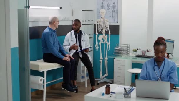 Африканский Американский Врач Консультирует Пожилого Человека Болезнью Давая Рецепт Лекарства — стоковое видео