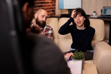 Stressed woman talking to counselor about marriage problems, attending couple therapy with husband and specialist. Trying to solve relationship conflict with professional support.