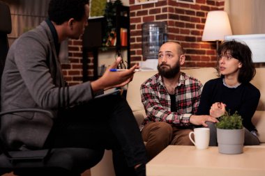 Caucasian partners trying to solve relationship problems with professional psychologist at therapy session. Giving counseling advice and support, feeling happy about reconciliation and holding hands.