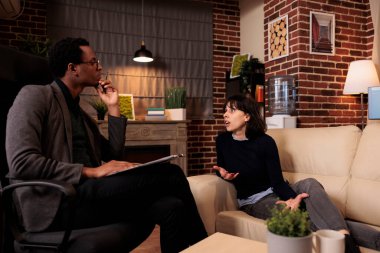 Female patient laying on sofa at psychotherapy session with therapist, talking about stress and problems. Receiving support and help from professional counselor, behavior guidance.