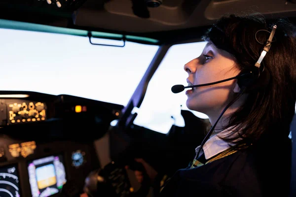 Female copilot flying plane from cockpit with dashboard command and control panel, using steering wheel and control panel for windscreen navigation. Woman using lever to fly aircraft.