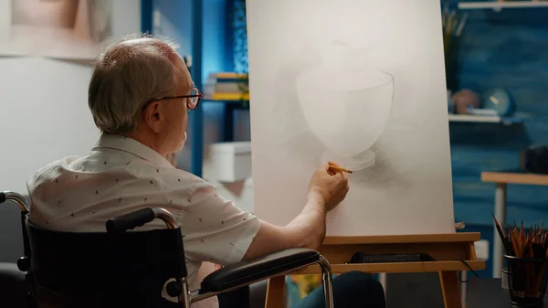 Male wheelchair user drawing vase design sketch on canvas, using professional tools and equipment. Suffering from physical disability and health condition, draw artwork masterpiece.