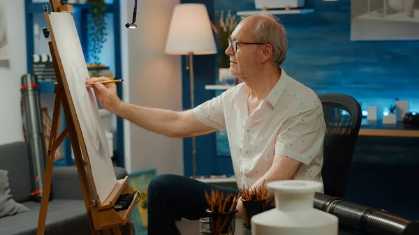 Senior artist drawing professional artwork with vase model, creating authentic masterpiece with artistic tools and equipment. Using pencils and creative skills to draw sketch. Handheld shot.