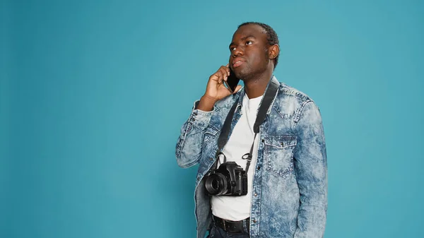 Νεαρός Φωτογράφος Μιλάει Στο Κινητό Τηλέφωνο Πάνω Από Μπλε Φόντο — Φωτογραφία Αρχείου
