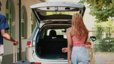 Married people putting baggage inside vehicle while going on field trip. Couple loading voyage luggage and trolleys inside car trunk while getting ready for holiday citybreak departure