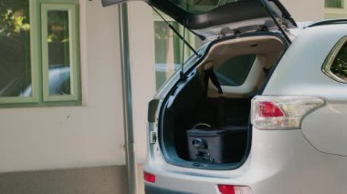 Grandparents, mother and daughter getting ready for summer citybreak while putting baggage and trolleys inside vehicle. Family going on holiday vacation while loading luggage inside car trunk