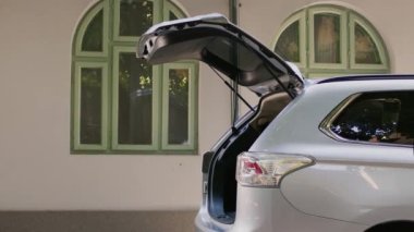 Retired couple loading voyage luggage in car trunk while going on marriage anniversary summer citybreak. Elderly tourists getting ready for field trip while putting baggage and trolleys inside vehicle