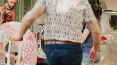 Casual people going on holiday field trip while putting luggage inside vehicle. Family loading voyage baggage and trolleys inside car trunk while going on summer vacation citybreak.