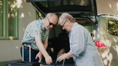 Retired people loading voyage baggage and trolleys inside vehicle while going on holiday field trip. Senior couple putting luggage in car trunk while getting ready for summer citybreak departure