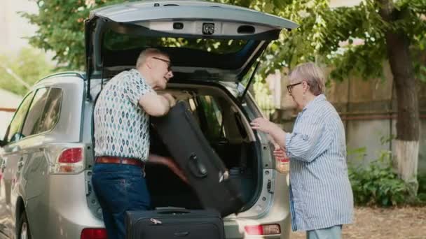 Lovely Senior Couple Putting Luggage Car Trunk While Getting Ready — Vídeos de Stock