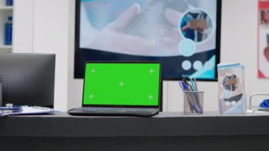 Greenscreen on laptop at hospital reception desk in medical waiting area with no people. Chroma key display with isolated copyspace and blank mockup background on computer pc.