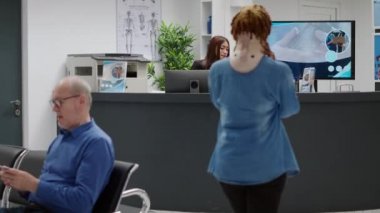 Patient with cervical collar having appointment with medic, waiting at hospital reception desk to attend examination. Woman with injury after accident wearing medical neck foam at facility.