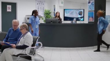 Female patient paying consultation with credit card at reception desk, attending checkup visit appointment. Woman talking to receptionist to pay medical consultation at clinical counter.
