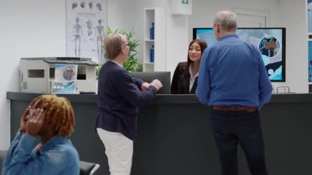 Senior People Talking Receptionist Hospital Reception Desk Asking Medical Appointment — Vídeo de stock