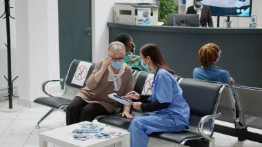 Kıdemli hasta, kovid 19 salgını sırasında Asyalı hemşireyle görüşüyor. Hastane resepsiyonunda koronavirüsün önlenmesinden bahsediyor. Bekleme odasına kontrol ziyareti, virüs koruması..