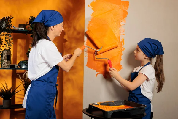 Little Child Helping Mom Painting Walls Using Orange Paint Color — Stockfoto