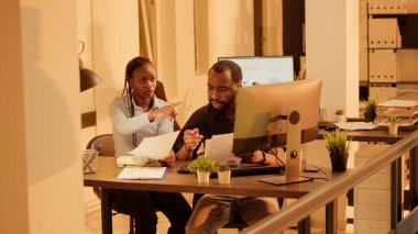 Team of coworkers brainstorming ideas to plan business report, analyzing information on documents and paperwork. Working on internet presentation with charts. Handheld shot.