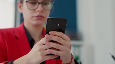 Ofis çalışanı masadaki akıllı telefondan internete bakıyor, mali istatistiklerle çalıştıktan sonra molada mesajlaşıyor. Finansal analist cep telefonu uygulamasını kullanıyor. Kapat..