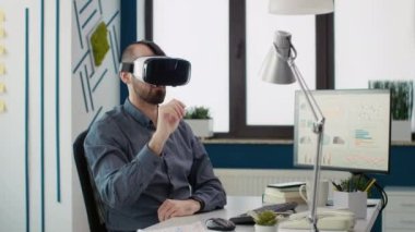 Başlangıç ofisinde sanal gerçeklik gözlüğü kullanan yönetici, etkileşimli görüş teknolojisiyle VR kulaklığı ile çalışıyor. İş adamı 3D simülasyon teknolojisiyle modern gözlüklerin keyfini çıkarıyor.